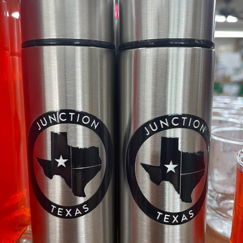 Junction Texas branded metal water bottles with a blue circle featuring the state of Texas and a white star marking Junction. The text 'Junction Texas' is written in white around the state.